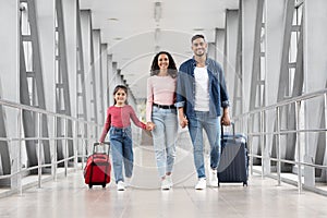 Beautiful Arabic Family Of Three With Suitcases Walking At Airport Terminal Together