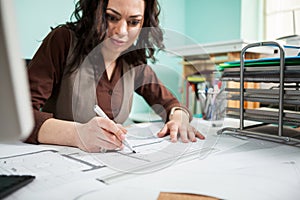 Beautiful architect at her working desk with blueprints in front