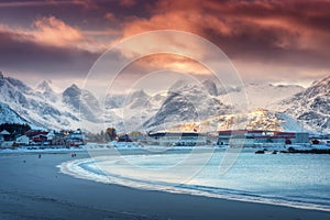 Beautiful arctic sandy beach, sea and snowy mountains at sunset