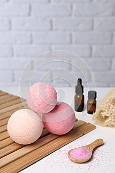 Beautiful aromatic bath bombs and sea salt on white table, space for text