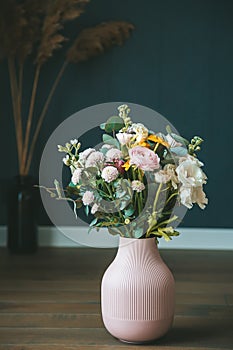 A beautiful arrangement of various flowers in a pink vase, set against a dark backdrop, evoking a sense of elegance and