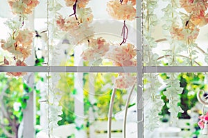 Beautiful artificial flowers hung on glass windows to decorate for a garden party.