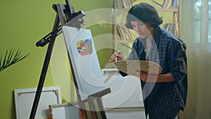 A beautiful artist woman is standing up while working on a canvas that she is painting beautiful art on as she is very