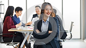 Beautiful Asain businesswoman sitting and holding arms with her team blur in background