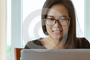 Beautiful asia woman smiling and looking at laptop screen