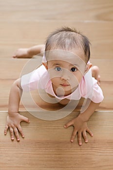 Beautiful asian baby girl while crawling up a stair.