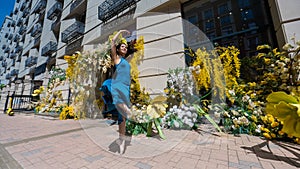 Beautiful Asian ballerina dances against the background of a building decorated with flowers.