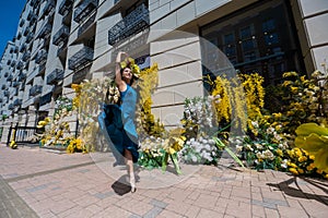 Beautiful Asian ballerina dances against the background of a building decorated with flowers.