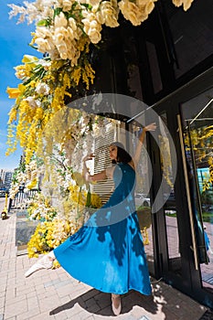Beautiful Asian ballerina posing against the backdrop of a building decorated with flowers.