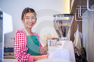 beautiful asian barista staff use coffee maker while looking at the camera with a smile on her face, Business and finance