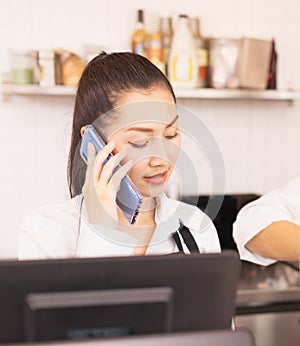 Beautiful Asian barista woman receives online drinking order via mobile phone for delivery takeaway coffee to customer from cafe