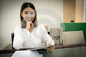 Beautiful asian business woman in close-up shot is confidence in her own sales and sitting while holding tablet with smile.