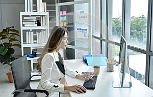 Beautiful Asian business woman looking at computer laptop screen to working in office