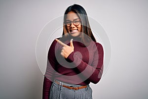 Beautiful asian business woman wearing casual sweater and glasses over white background cheerful with a smile of face pointing
