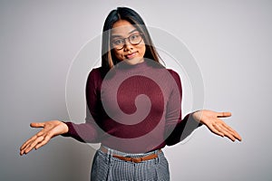 Beautiful asian business woman wearing casual sweater and glasses over white background clueless and confused expression with arms
