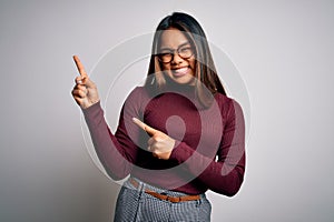 Beautiful asian business woman wearing casual sweater and glasses over white background smiling and looking at the camera pointing