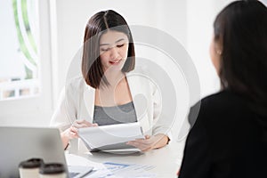 Beautiful asian business woman is reading the resume and gives the interview as a human resource for company recruitment with an photo