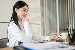 A beautiful Asian businesswoman or female office employee is working on her laptop at her desk