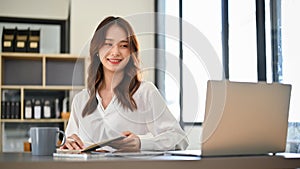 Beautiful Asian businesswoman or female secretary working at her desk in the office