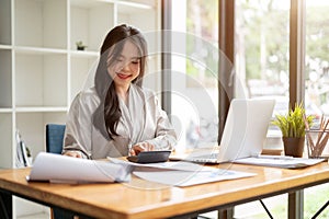 A beautiful Asian businesswoman is focusing on her work at her desk in the office
