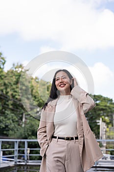 A beautiful Asian businesswoman in a trendy business suit is walking in the city on a brighten day