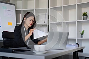 Beautiful asian businesswoman woman using calculator and laptop for doing finance on an office desk, tax, report