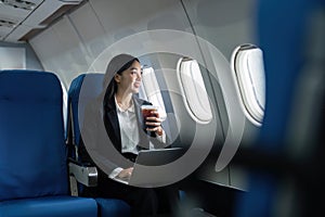 Beautiful Asian businesswoman working with laptop in aeroplane. working, travel, business concept