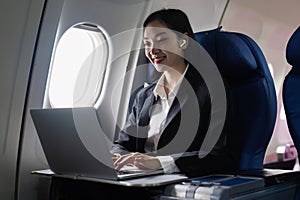 Beautiful Asian businesswoman working with laptop in aeroplane. working, travel, business concept