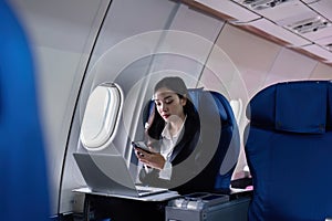 Beautiful Asian businesswoman working with laptop and mobile in aeroplane. working, travel, business concept