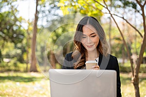 A beautiful Asian businesswoman is working remotely in a park in the afternoon