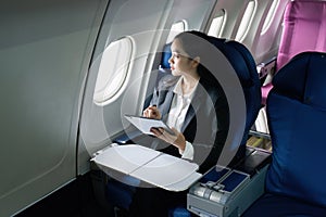 Beautiful Asian businesswoman working with tablet in aeroplane. working, travel, business concept