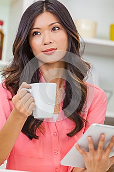 Asian Chinese Woman Using Tablet Computer Drinking Coffee or Tea