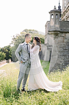 Beautiful asian couple, woman in wedding dress, man in suit, posing outdoors near the old ancient castle