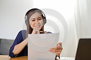 Beautiful Asian female college student studying an online class at home