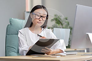 Beautiful asian female doctor doing paperwork in clinic office, nurse working with computer and writing