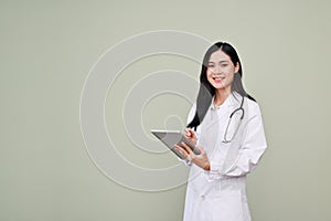 Beautiful Asian female doctor holding a digital tablet, standing isolated over grey background