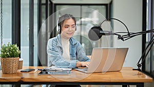 A beautiful Asian female podcaster or radio host working in her studio