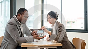 A beautiful Asian female real estate agent is having a meeting with an African American male client