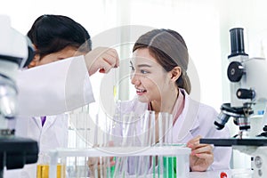 Beautiful Asian female teacher in lab coats teaching schoolgirl child to do science experiments. Happy young scientist kid girl