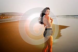 Beautiful Asian girl in a bathing suit on the beach at sunset.