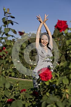 Beautiful Asian girl dancing among red roses