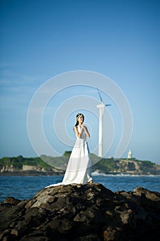 Beautiful Asian girl dressed in white dress enjoying sea breeze by the sea