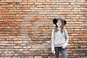 Beautiful asian girl in fashionable dress, standing in front of red brick wall background with copy space