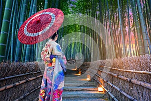 Beautiful Asian girl in kimono holding an umbrella visits a bamboo forest in Kyoto, Japan