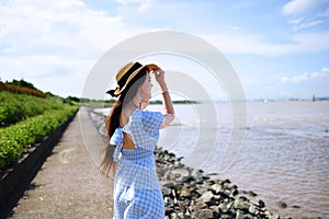Beautiful asian girl in long blue dress on the bank of the embankment