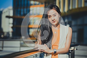 Beautiful Asian girl model in white dress posing at the modern glass style office city background.