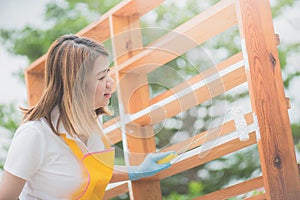 Beautiful Asian girl paiting wooden shelf by roller