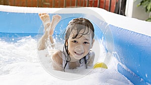 Beautiful Asian girl playing in an inflatable pool. Playing in the water at home during the summer.