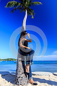 Beautiful asian girl posing at the beach near to palm tree
