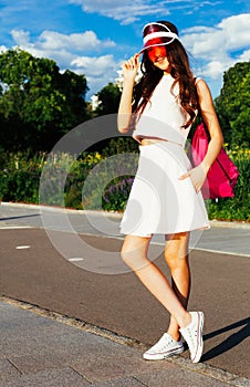 Beautiful asian girl posing on a vintage roller skates in outfit, sneakers and fashionable red Brim Visor Hat on a